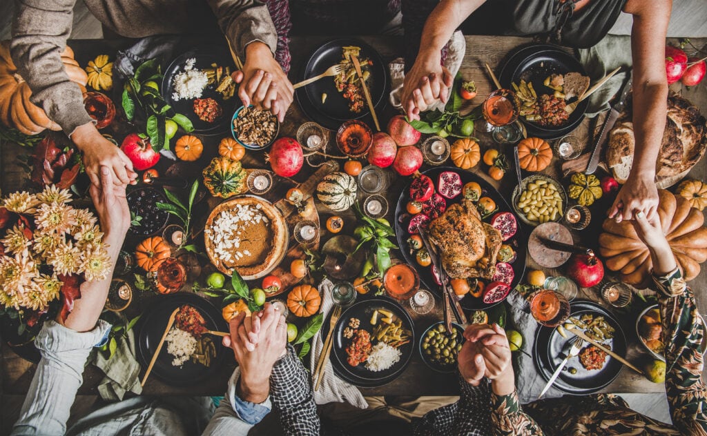 Thanksgiving feast with family sharing food around a decorated table filled with autumnal dishes and pumpkins