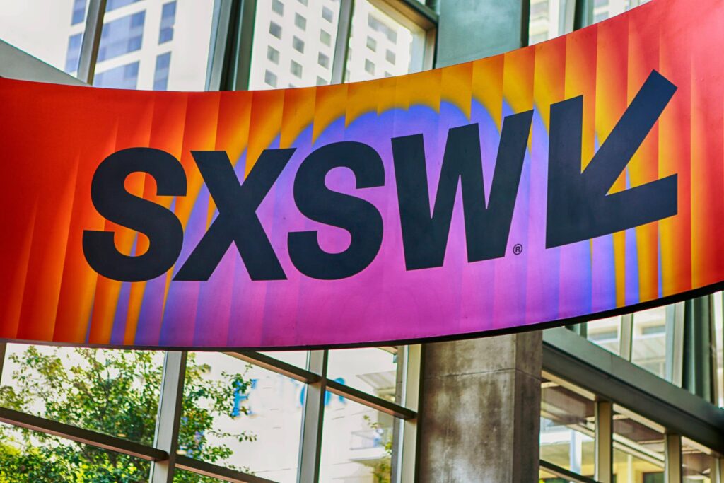 Colorful SXSW banner displayed indoors with modern building background.