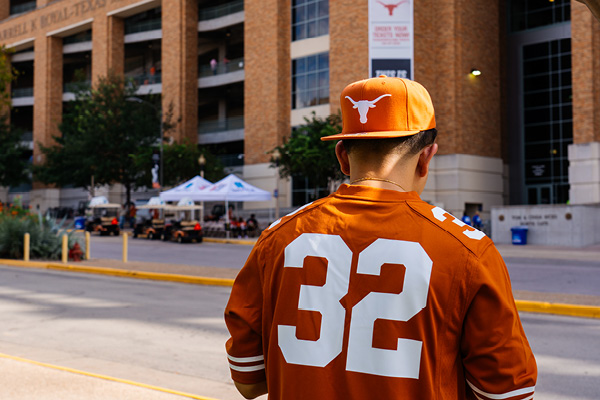 A man dressed in Longhorns team gear heads to a game at Darrell K Royal Stadium on the University of Texas campus.